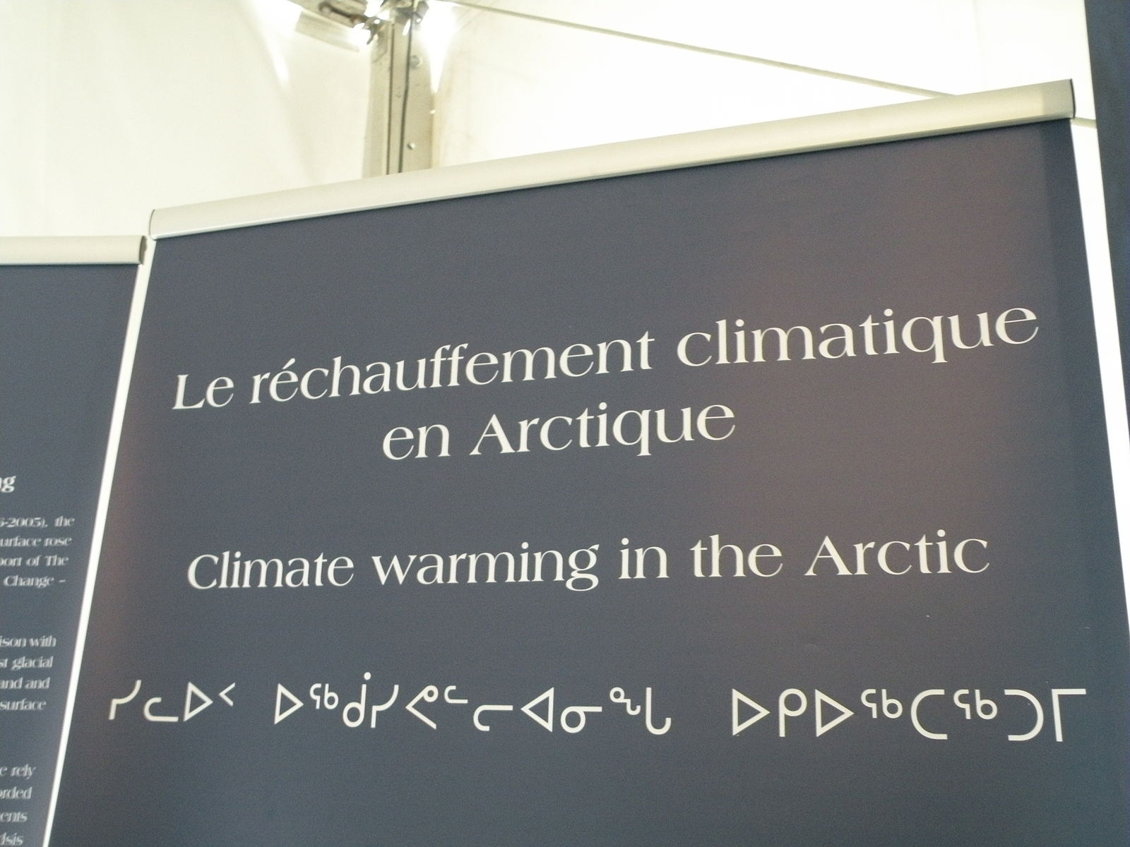 Sign for a conference with title of a session (Climate warming in the Arctic) in French, English, and Inuktitut
